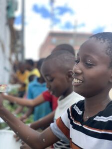 Children smiling in front of a community mural in Kitui