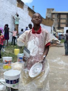 Children smiling in front of a community mural in Kitui