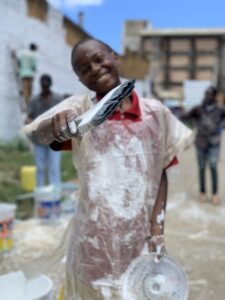 Children smiling in front of a community mural in Kitui